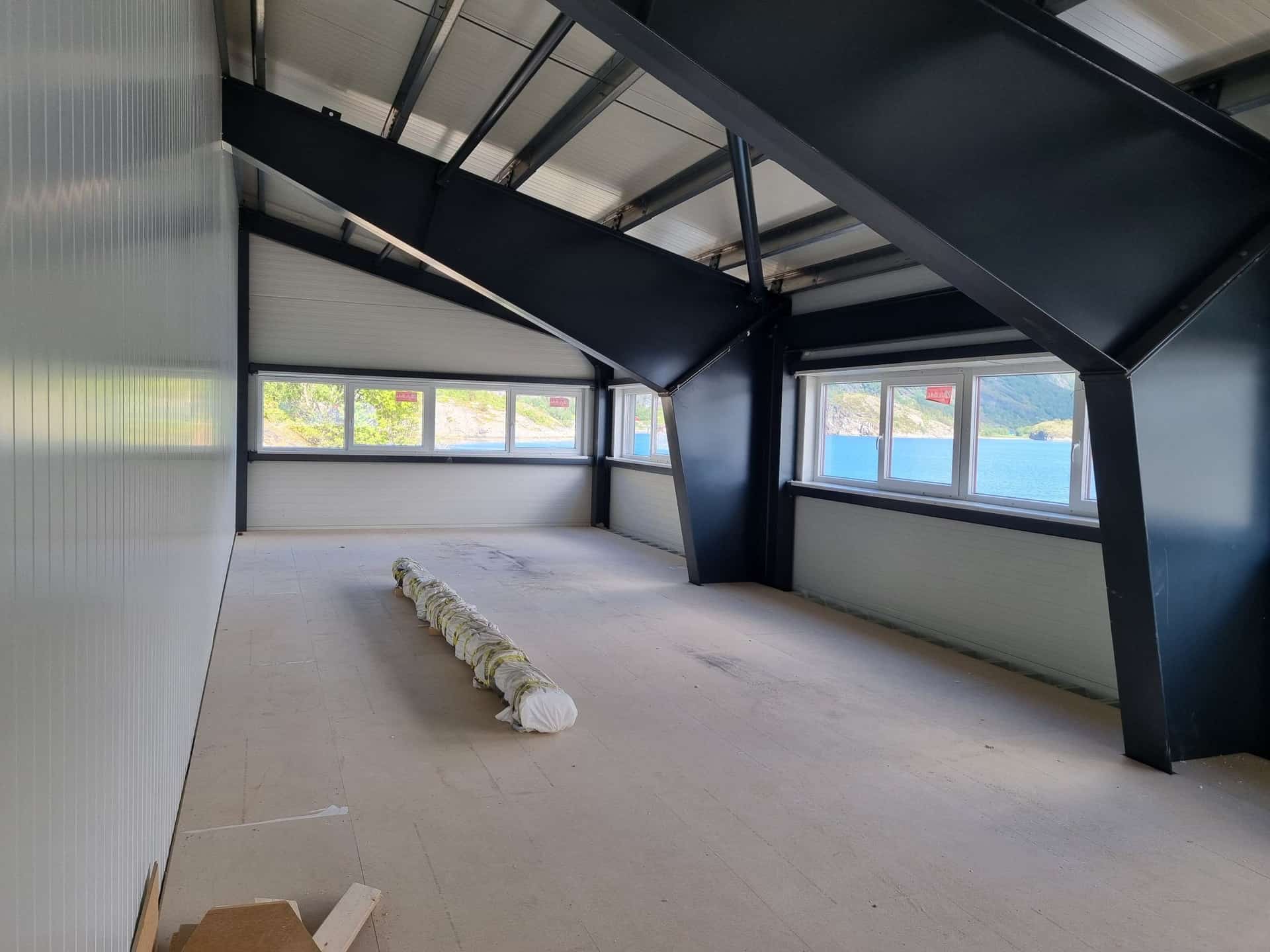 Oficina en entreplanta con ventanas corridas y la estructura de acero vista