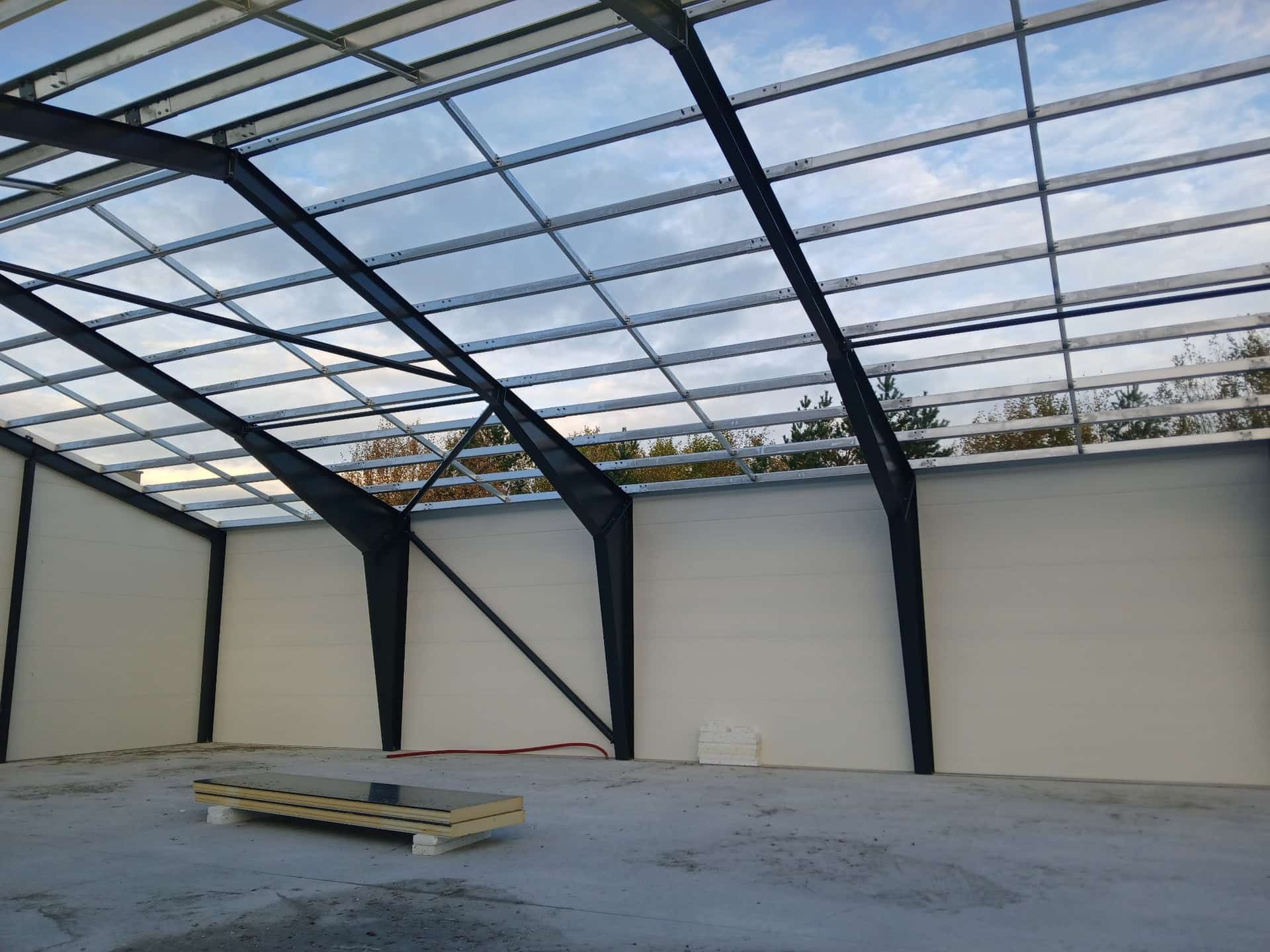 Interior de una nave con los pórticos, las correas de cubierta y el cerramiento de panel sándwich ya colocado