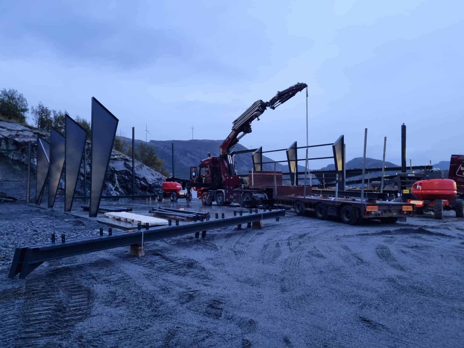 Crane truck unloading steel sections next to the first erected columns