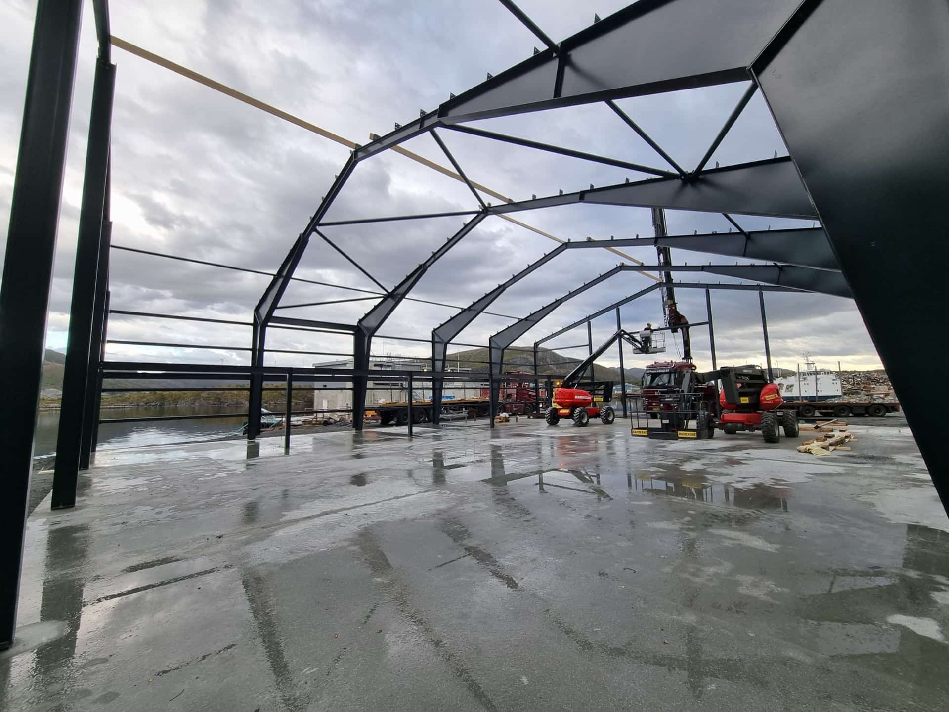 Inside a building under construction, with the steel portal frames erected on the slab