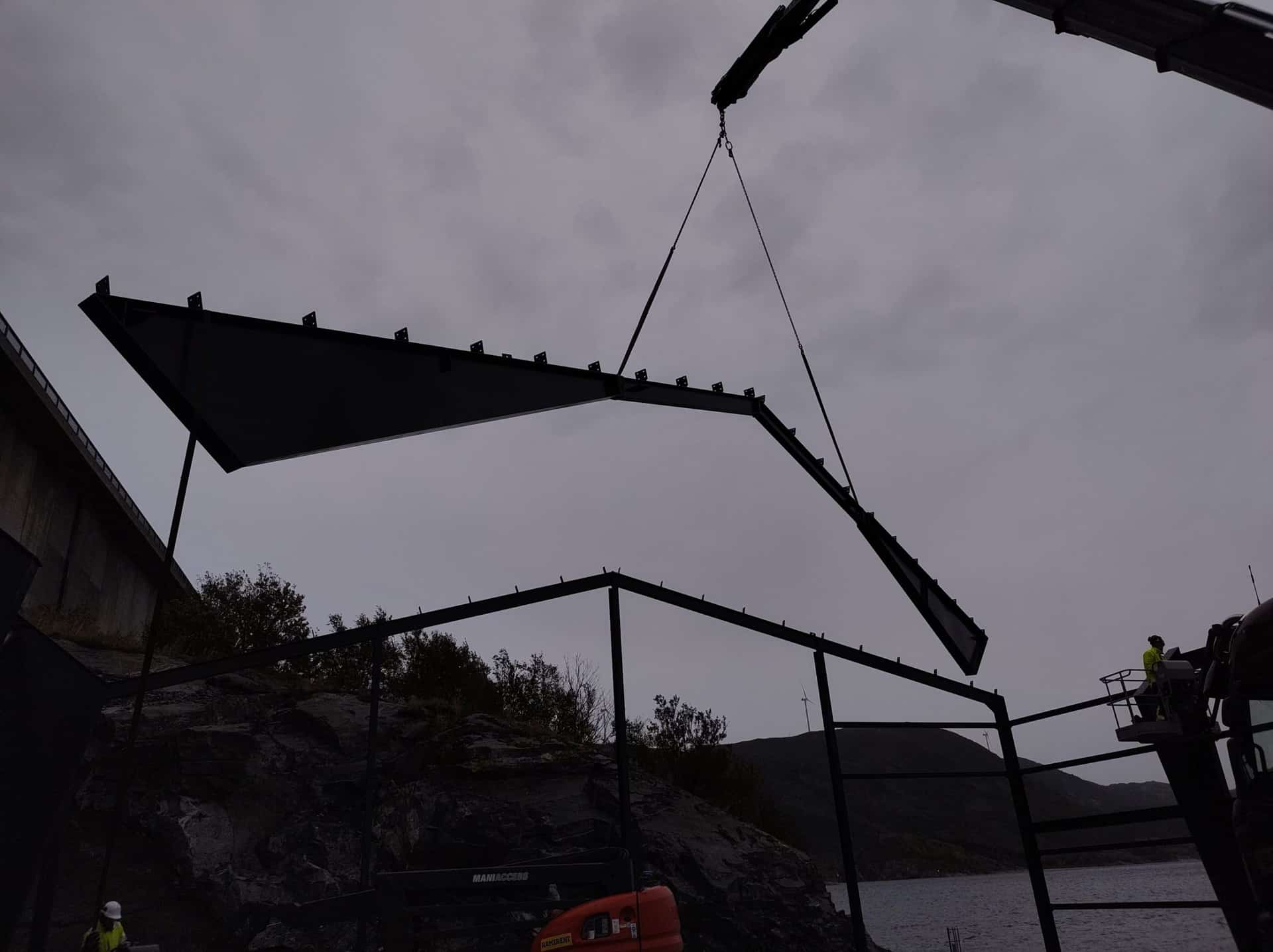 Crane lifting a steel portal rafter into position