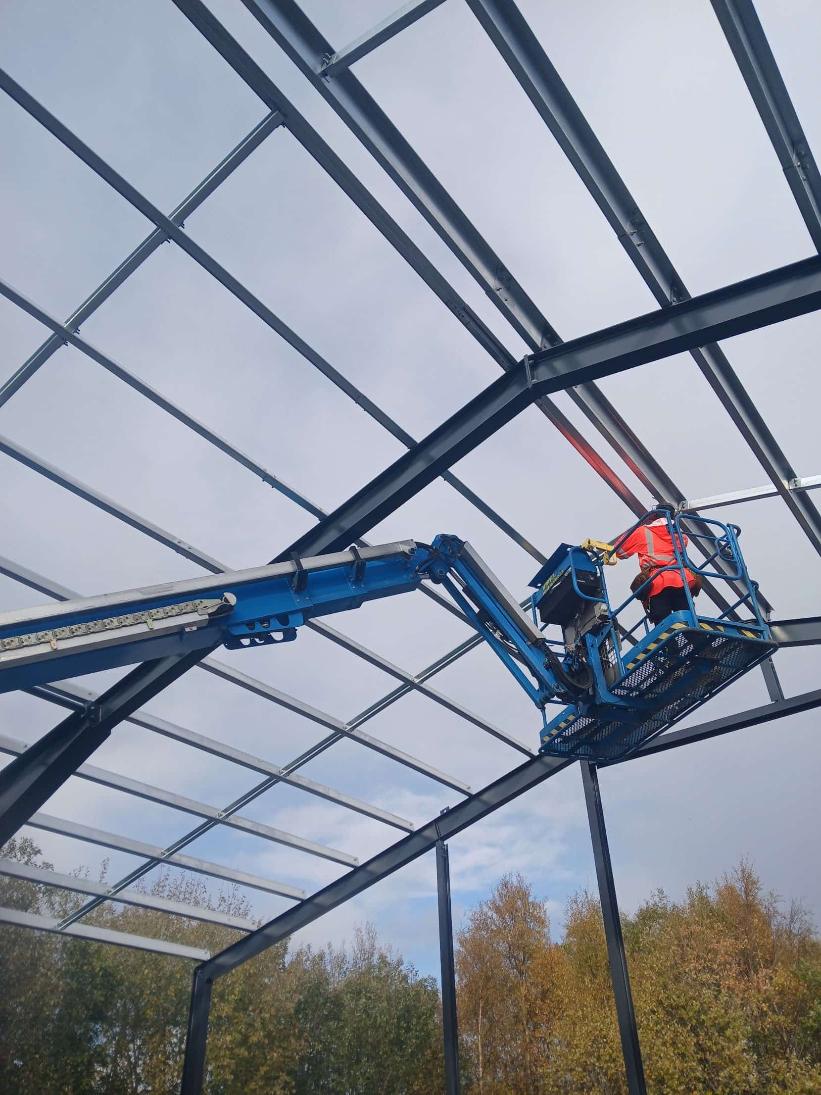 Erectors fitting roof purlins from a boom lift